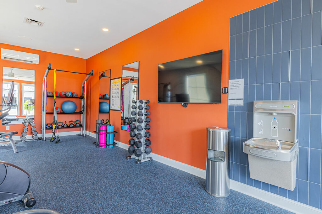 Fitness center with water and cleaning stations, free weights, and cardio equipment