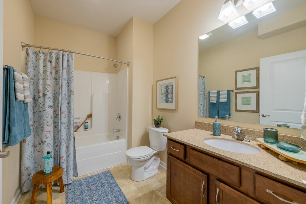 Stylish bathroom with single vanity, bathtub, and ceramic tiles in apartment model
