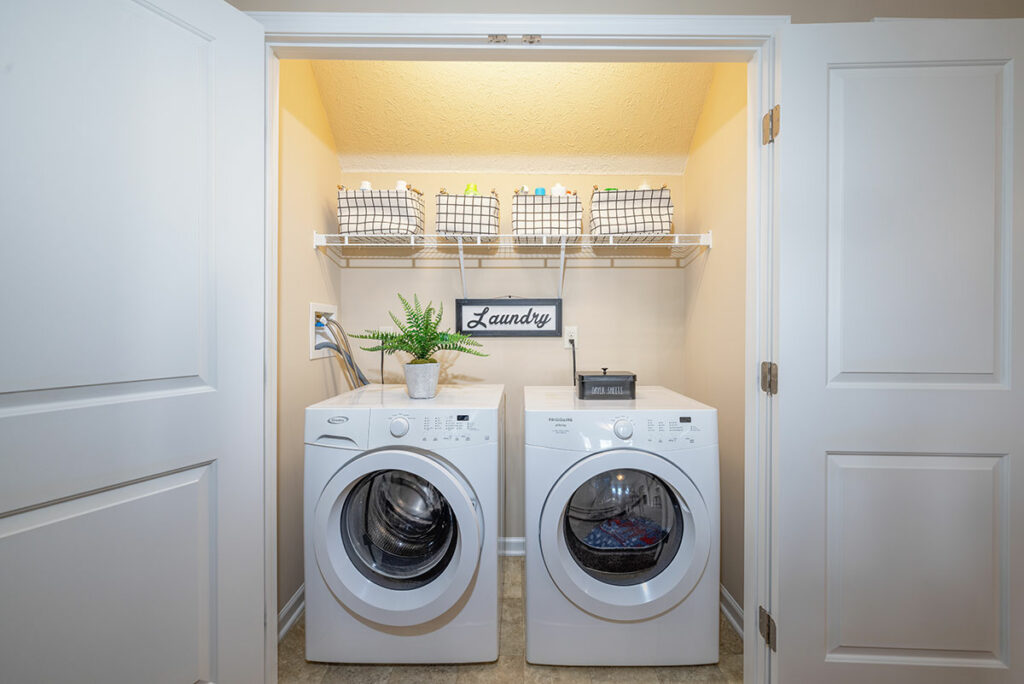 Laundry room with two full-size washer and dryer units in apartment model