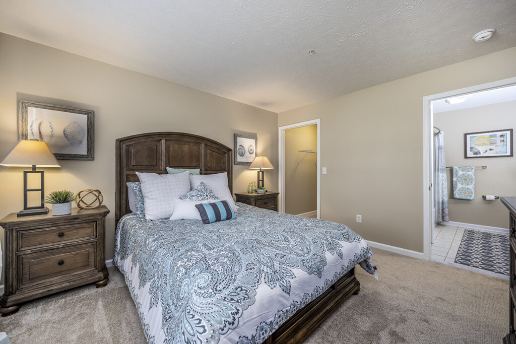 A master bedroom featuring brand-new carpeting, an attached walk-in closet, and a private bathroom with tile flooring. The bedroom offers ample space and natural light, leading into a well-organized closet and a modern bathroom equipped with a shower and vanity.