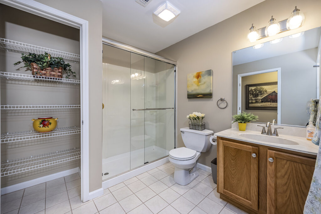 Master bathroom featuring a sleek shower, spacious vanity, and a convenient storage closet at The Hammocks at Orchard Park. Perfect for keeping essentials organized.