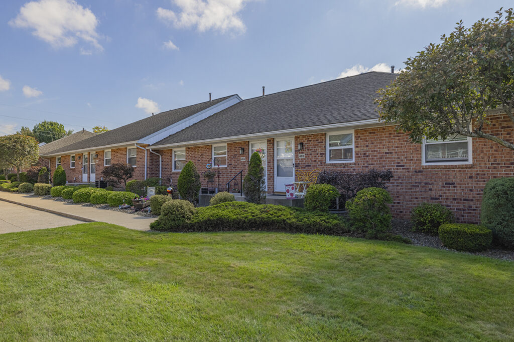 Exterior view of Idyllbrook Senior Living in Erie, PA featuring a brick facade, single-level homes with private entrances, and beautifully landscaped grounds.