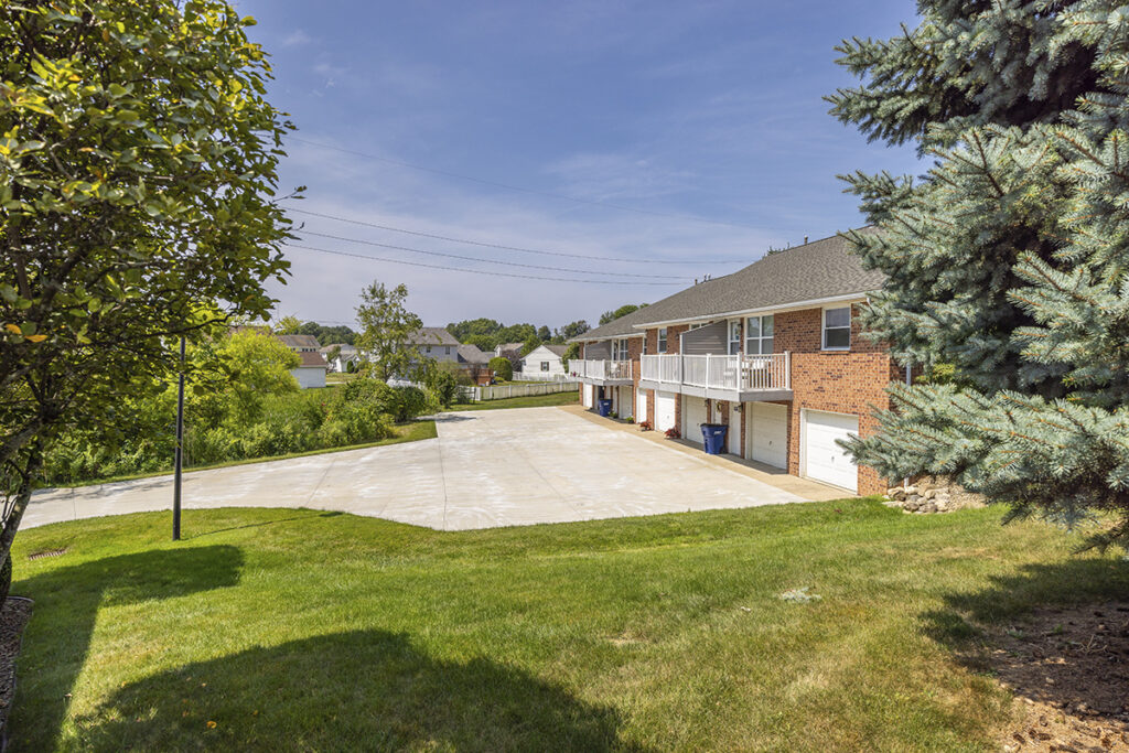 Side view of the back of Idyllbrook Senior Living homes in Erie, PA, showcasing two-story patios and private garage entrances.