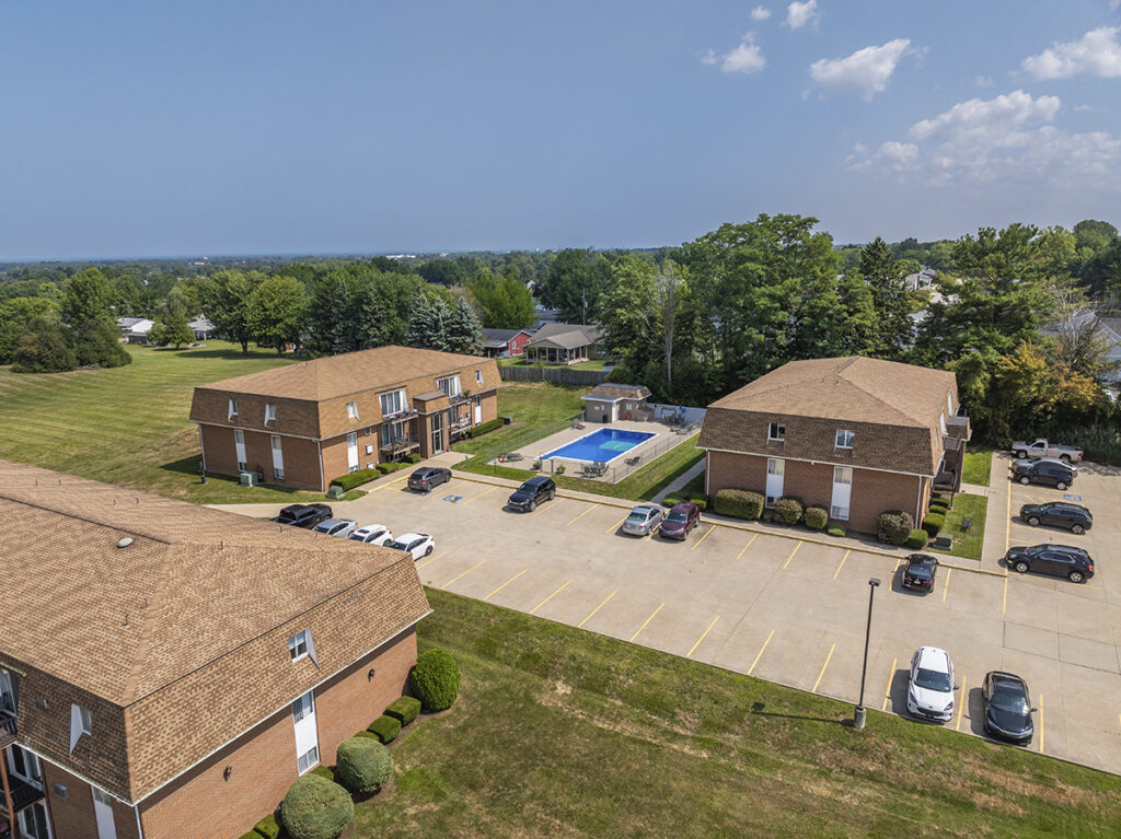 Aerial view of Royal Villa Apartments in Erie, PA, showcasing the brick building, controlled entrances, and the inground swimming pool.