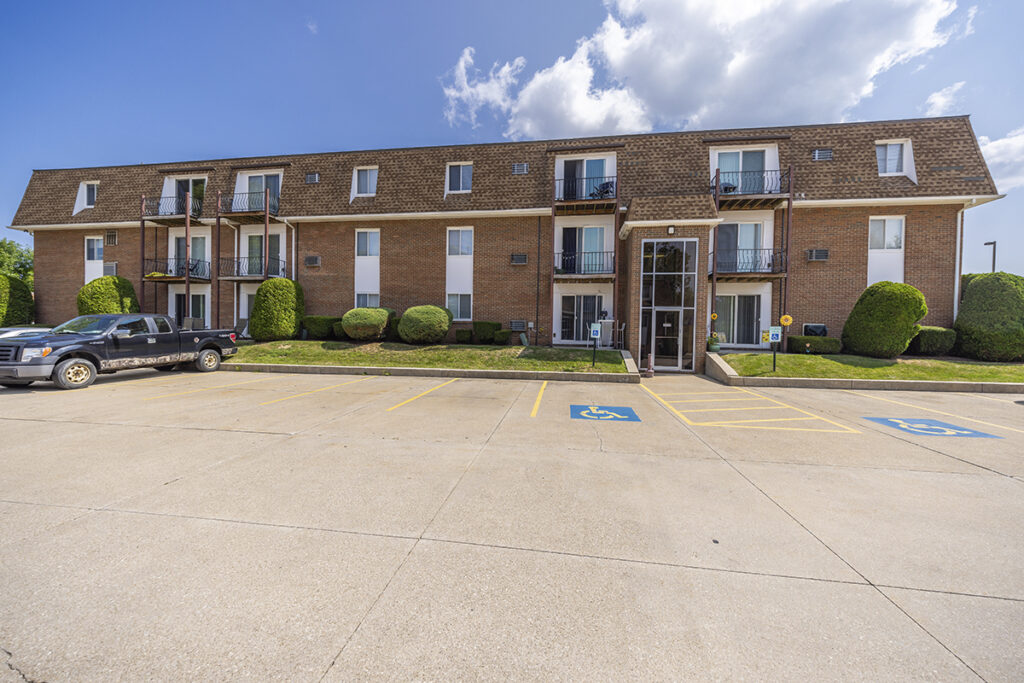 Exterior view of Royal Villa Apartments in Erie, PA, featuring a brick facade, controlled building entrances, and private patios or balconies.