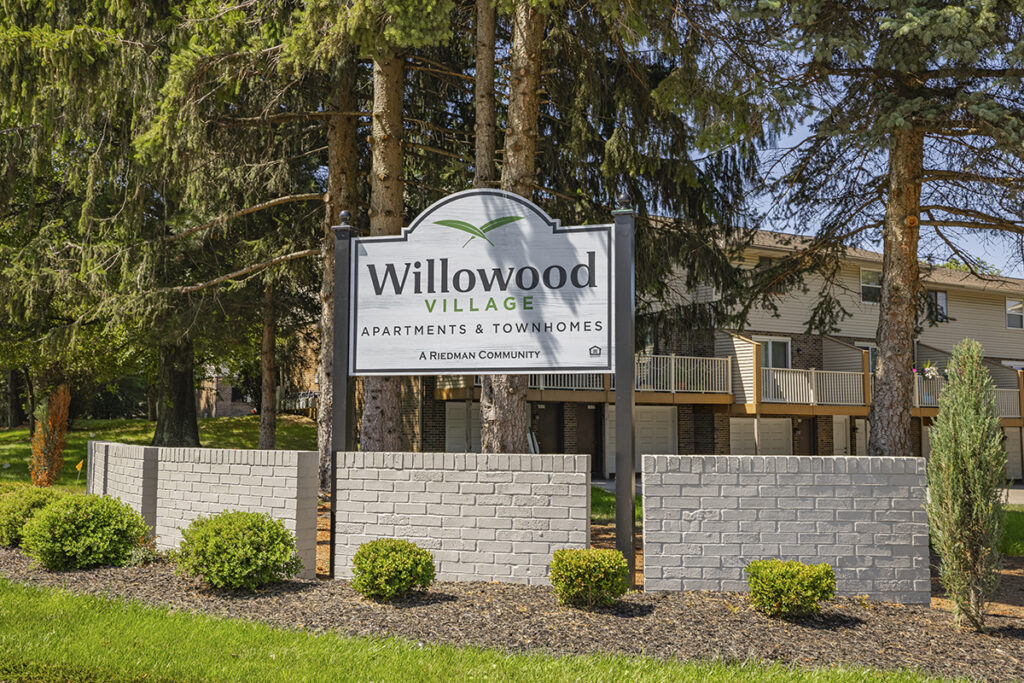 Community sign for Willowood Village Apartments and Townhomes in Erie, PA, featuring well-maintained landscaping and a welcoming entrance.