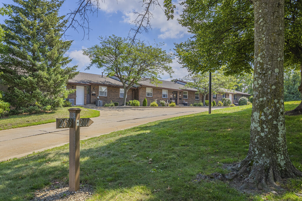 A tranquil exterior view of homes with charming brick facades and private entrances, set in a serene and picturesque environment, creating a welcoming and peaceful living space.