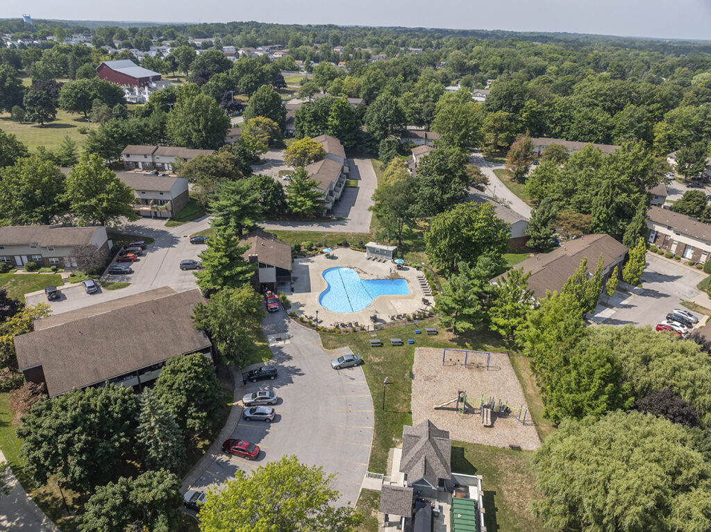 Aerial view of Willowood Village Apartments & Townhomes, highlighting the layout of the community along with common areas such as the pool, playground, and mail center.