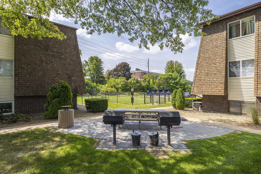 Picnic area with seating and tables, offering a view of the adjacent dog park, providing a relaxing spot with a nearby recreational space for pets.