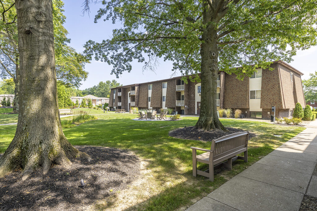 Courtyard view featuring beautiful mature landscaping, a picnic area, and a nicely paved path, creating a welcoming and well-maintained outdoor space.