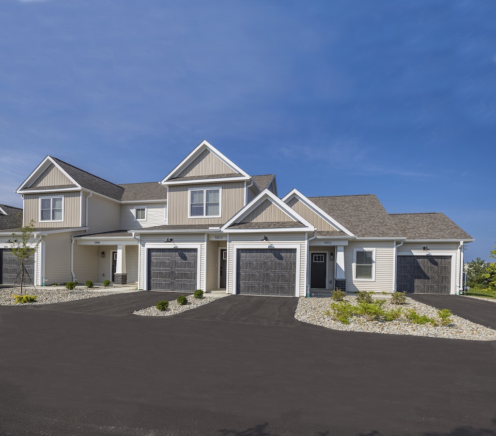 Building exterior with light gray siding, and gabled roofs, set against a clear blue sky.
