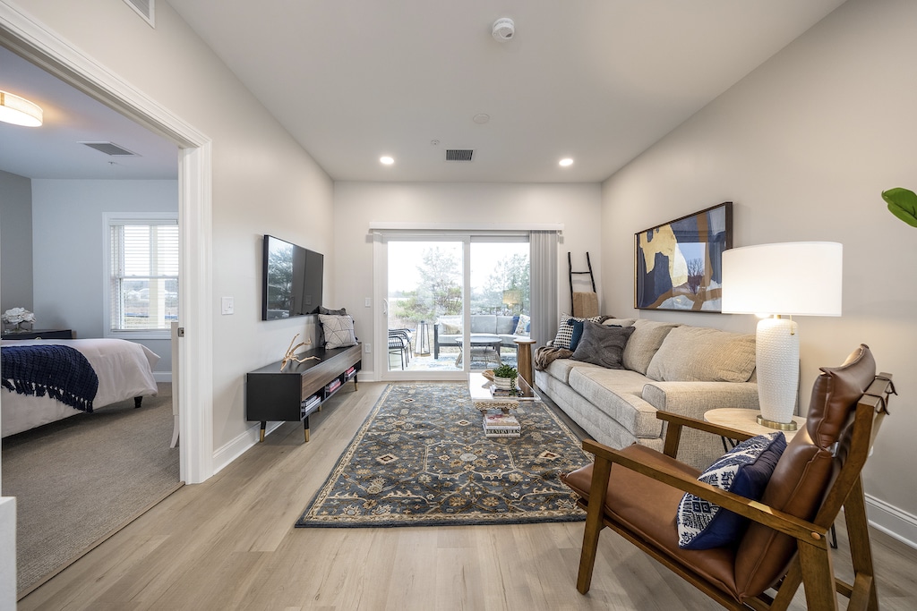 Spacious living room with stylish LVP flooring, opening onto a charming patio - ideal for relaxation and entertainment. Explore our apartment rentals for the perfect blend of comfort and modern living.