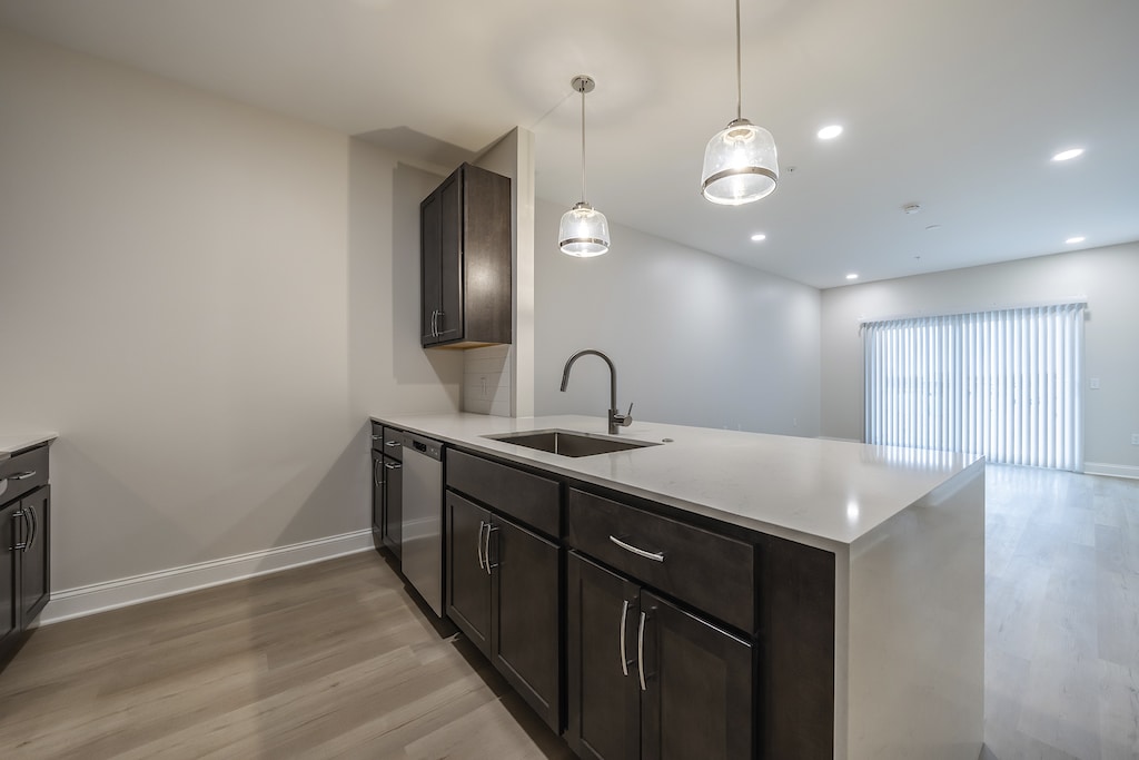 Modern kitchen with sleek quartz countertops, luxurious dark maple cabinetry, and a spacious breakfast bar illuminated by elegant pendant lighting.