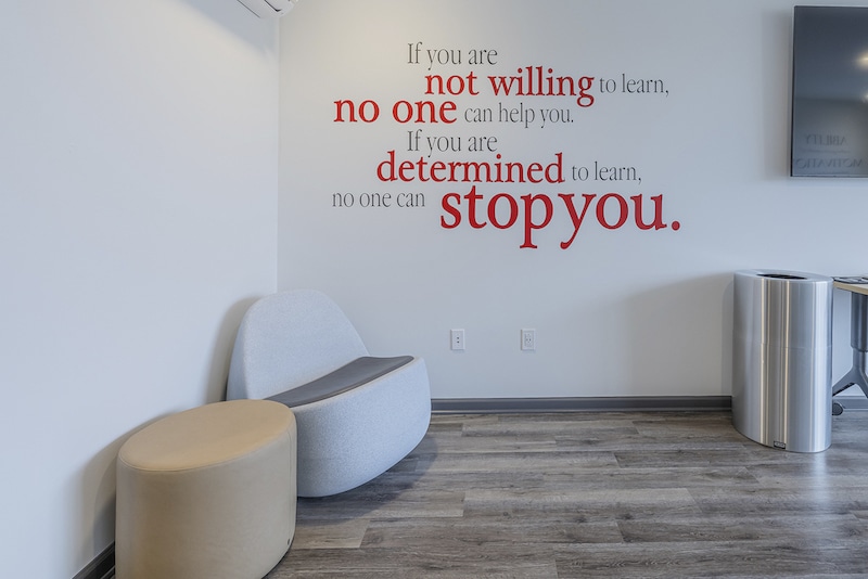 A waiting area with modern seating and a wall quote reading, "If you are not willing to learn, no one can help you. If you are determined to learn, no one can stop you.