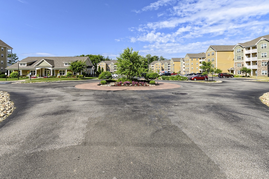 Roundabout with a landscaped center, surrounded by residential buildings and parked cars under a clear blue sky.