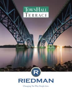 A view of two illuminated steel bridges over calm water at dusk, with text reading "TownHall Terrace" and "Riedman: Changing The Way People Live.