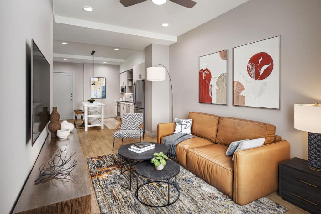 Modern living room with a brown leather sofa, abstract wall art, and a patterned rug. A round coffee table and an adjacent dining area are visible. Ceiling lights and a floor lamp illuminate the space.