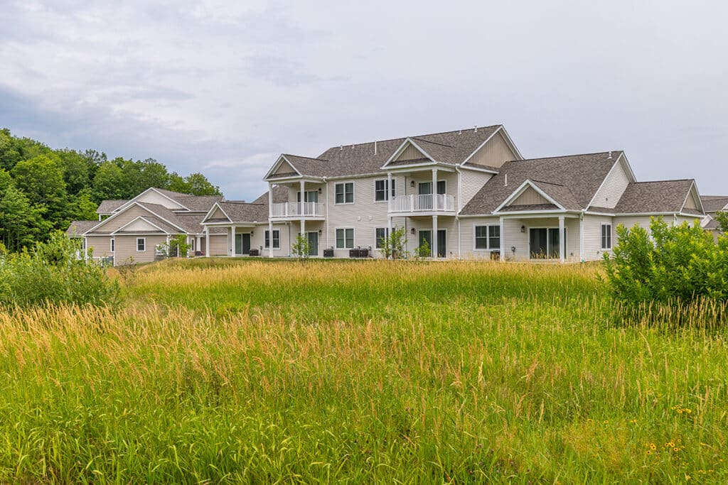 Rear view of one of the apartment building showcasing private balconies and private patios surrounded by tall grass and greenery for added privacy.