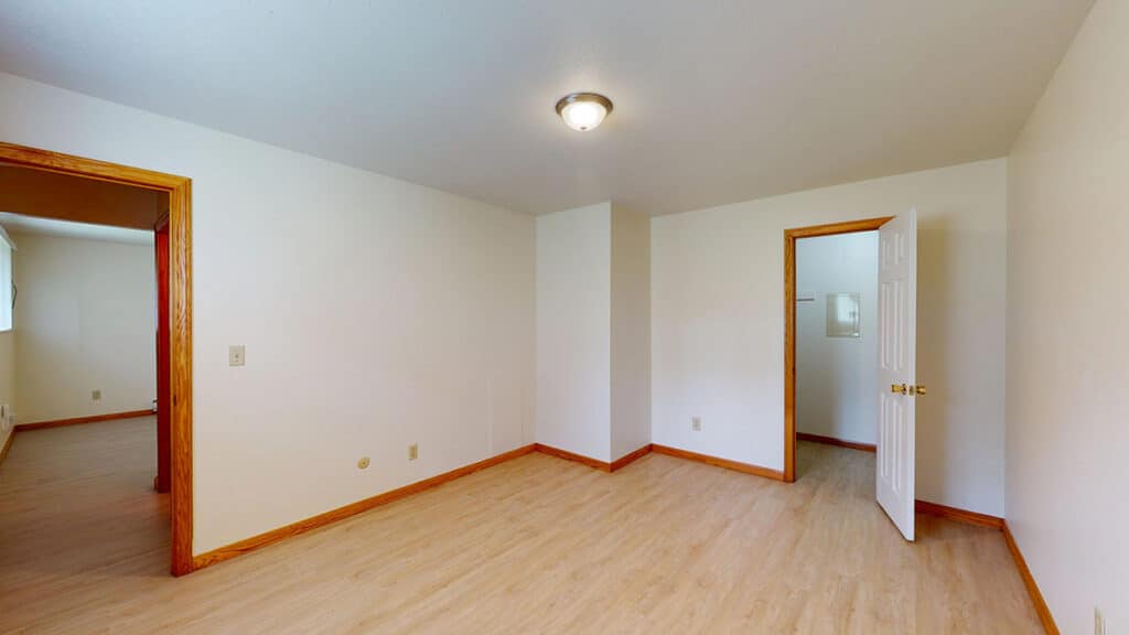Bedroom at Royal Villa Apartments in Erie, PA featuring wood-style flooring, neutral walls, and a walk-in closet. The space offers modern lighting and clean finishes, ideal for a comfortable rental home.
