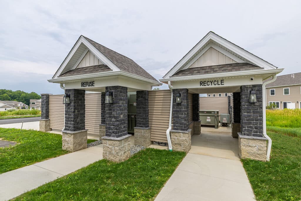 Convenient refuse and recycling center located in the heart of The Hammocks at Fairview community, featuring covered stone enclosures with lighting and easy resident access.