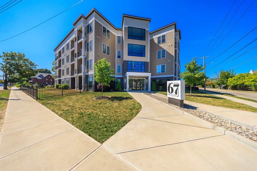 Exterior view of Six67 College Avenue in Elmira, NY with the community entrance, landscaping, and Six67 signage.