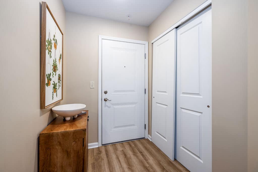 Entry hallway with wood-style flooring, built-in storage bench, wall hooks, and decorative plant at The Hammocks at Millcreek