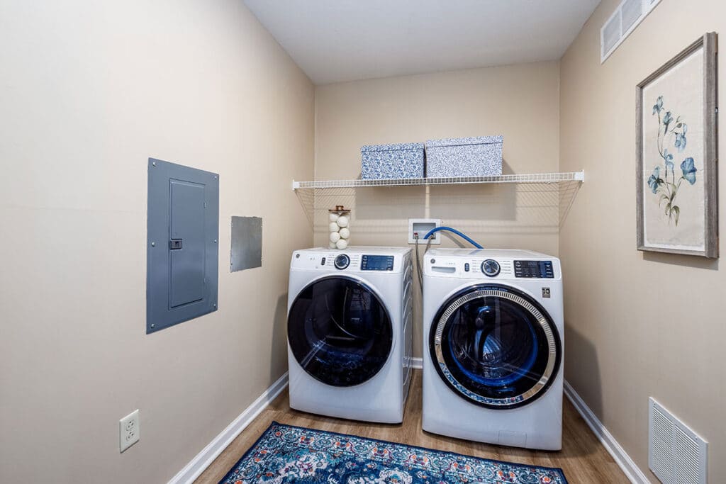 Laundry room with full-size washer and dryer and overhead storage shelf