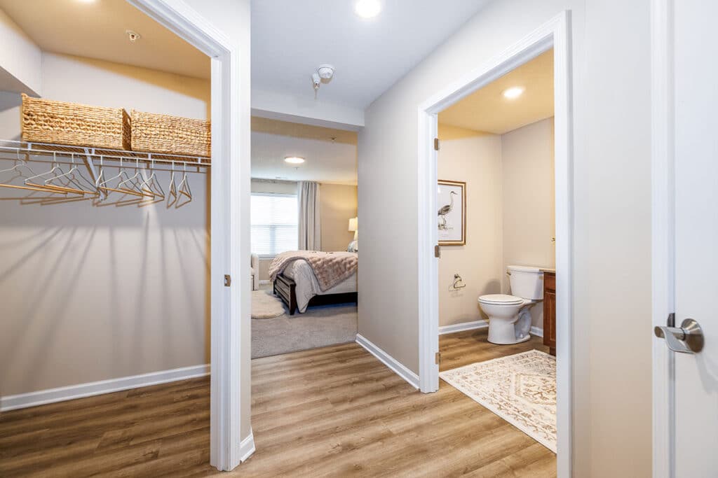 Interior master bedroom hallway with LVP wood-style flooring, walk-in closet, bathroom access, and view into the bedroom