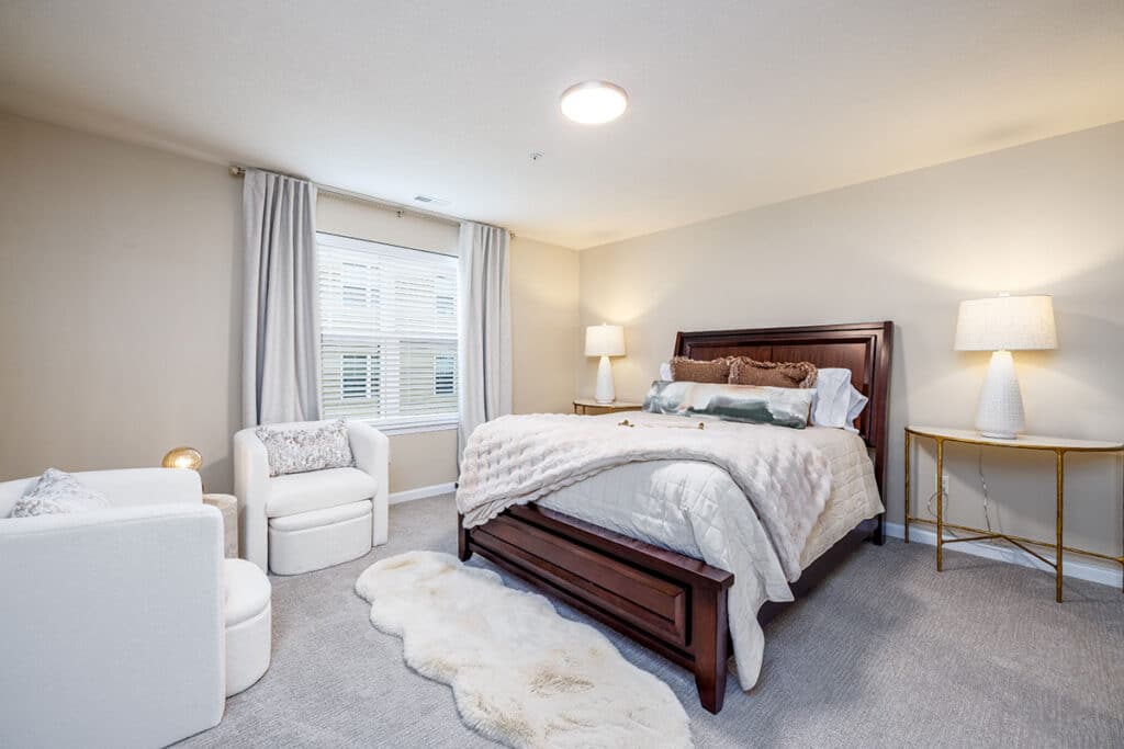 Primary bedroom with large window, neutral finishes, and dark wood bed frame
