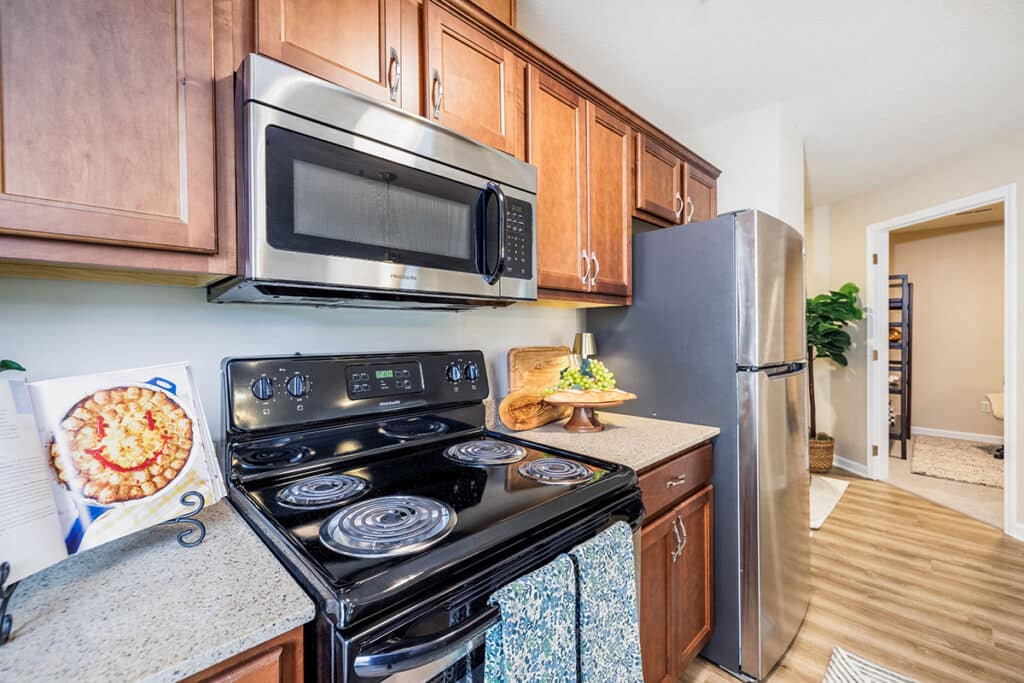 Kitchen with breakfast bar, stainless steel refrigerator, wood cabinetry, double-basin sink, and pendant lighting