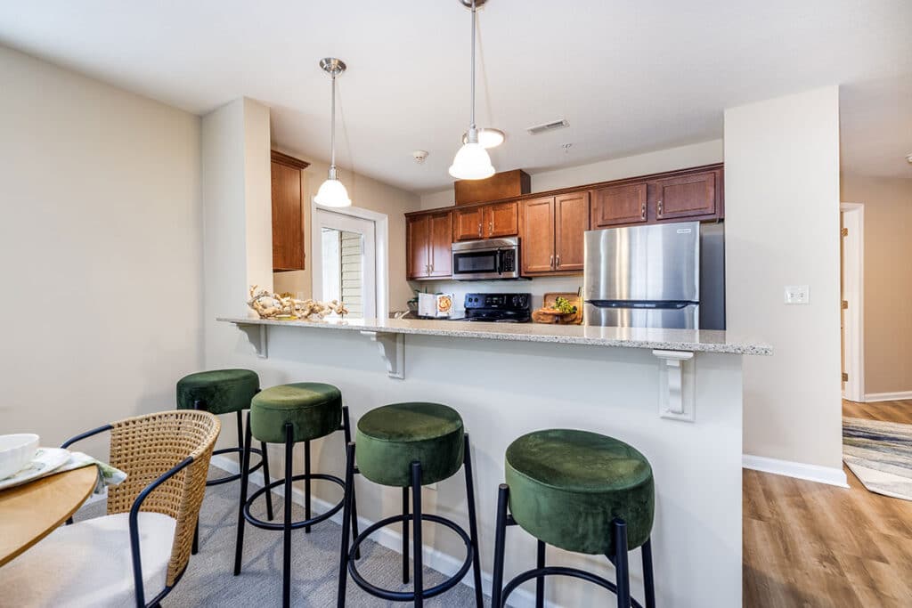 Kitchen with breakfast bar, pendant lighting, wood cabinetry, and stainless steel appliances at The Hammocks at Millcreek in Erie, PA
