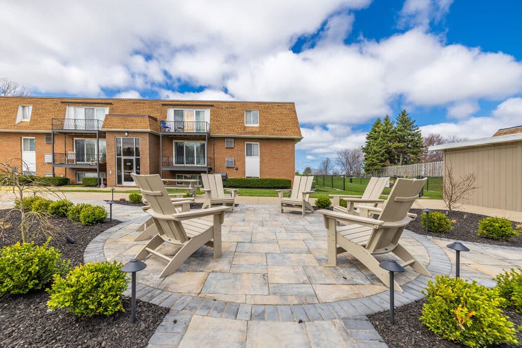 Landscaped courtyard seating area at Royal Villa Apartments in Erie, PA with Adirondack chairs and walking paths.