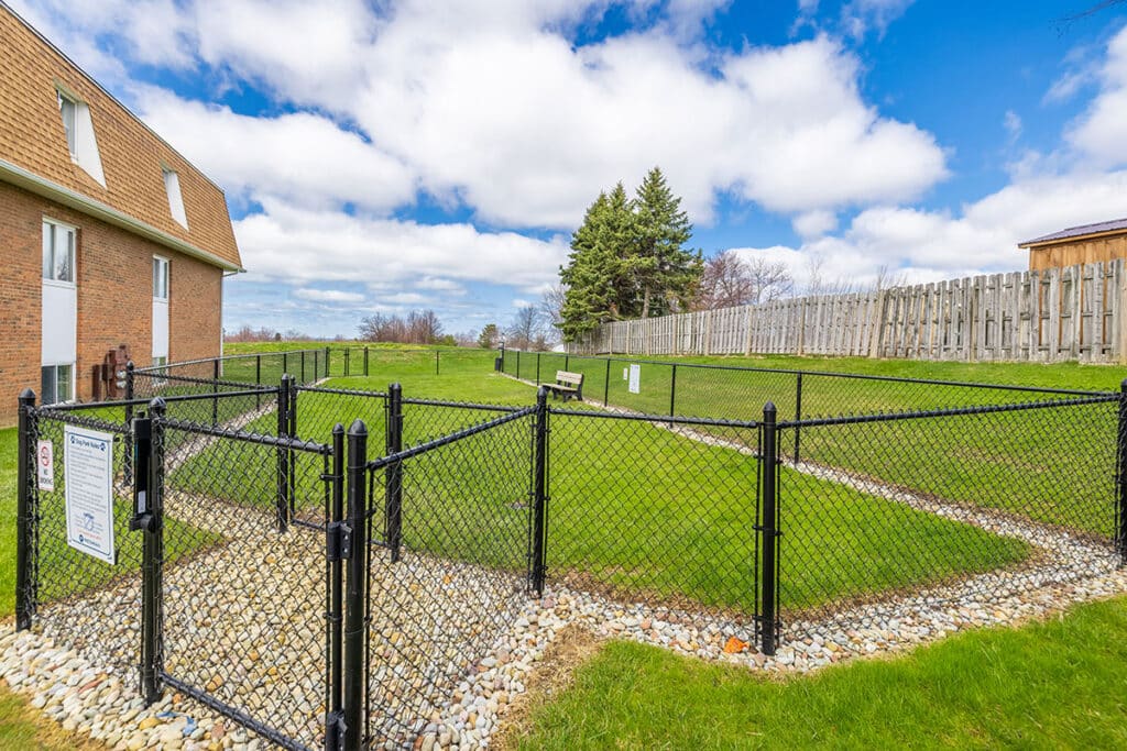 Fenced dog park at Royal Villa Apartments in Erie, PA with green lawn, walking path, and pet-friendly space.