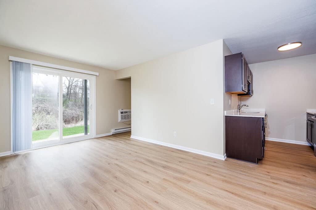 Remodeled one-bedroom home at Royal Villa Apartments in Erie, PA with wood-style flooring, sliding glass doors, and kitchen access.